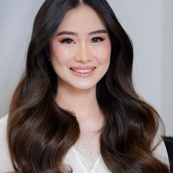 Portrait with long dark waves, warm-toned eye makeup and a soft pink glossy lip