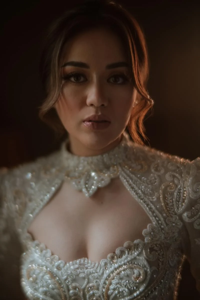 Portrait in warm light with a detailed beaded white gown, a jeweled collar and a softly styled updo